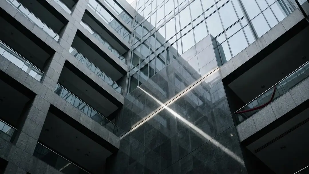 Stone and glass atrium of a financial district tower with a shaft of light