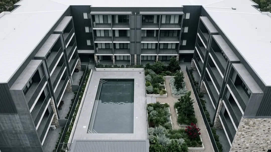 Aerial view of a residential complex courtyard with shared gardens and balconies