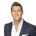 Professional man in suit jacket smiles confidently.